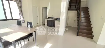 Modern duplex interior with sleek staircase and dining area, featuring natural light and minimalist design.
