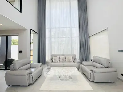 Luxurious modern living room with high ceilings and elegant gray furniture.