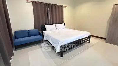 Spacious bedroom with modern decor and cozy seating area.