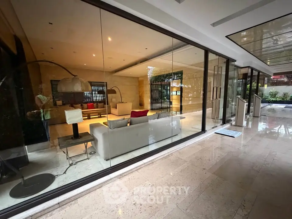 Luxurious modern building entrance with glass walls and elegant interior design.