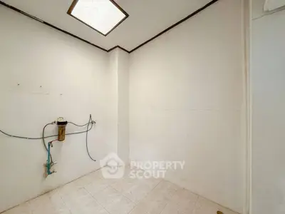 Spacious utility room with tiled floor and plumbing setup, ideal for laundry or storage.