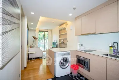 Modern open-layout kitchen with washing machine and cozy living area.