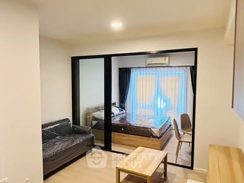 Modern studio apartment with glass partition, cozy living area, and natural light.