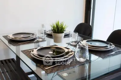 Elegant dining area with modern glass table and stylish black dinnerware set.