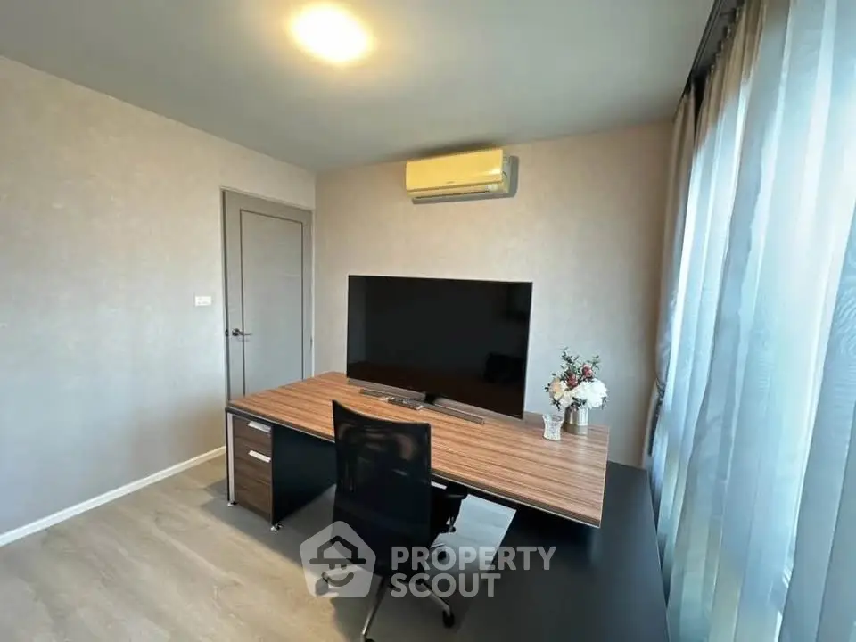 Modern study room with sleek desk, large TV, and air conditioning in a bright, airy space.
