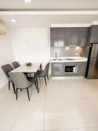 Modern kitchen with sleek cabinetry and dining area in a contemporary apartment.