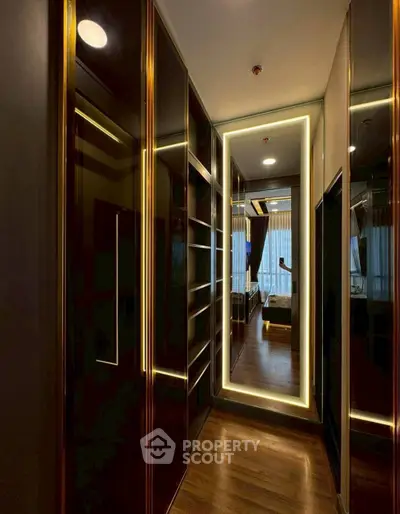Luxurious walk-in closet with elegant lighting and mirrored accents leading to a stylish bedroom.