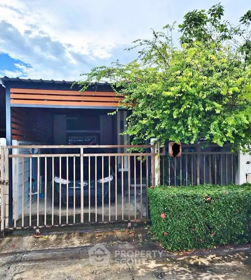 Charming single-story home with gated entrance and lush greenery, perfect for cozy living.