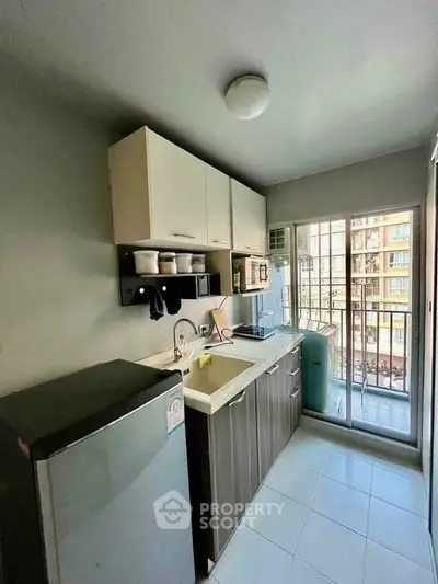 Modern kitchen with balcony view, featuring sleek cabinets and appliances in a compact layout.