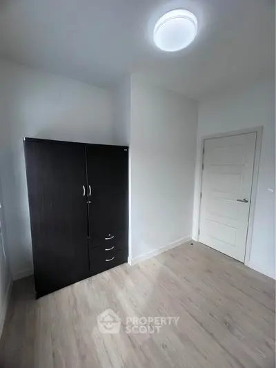 Minimalist bedroom with wooden flooring and dark wardrobe