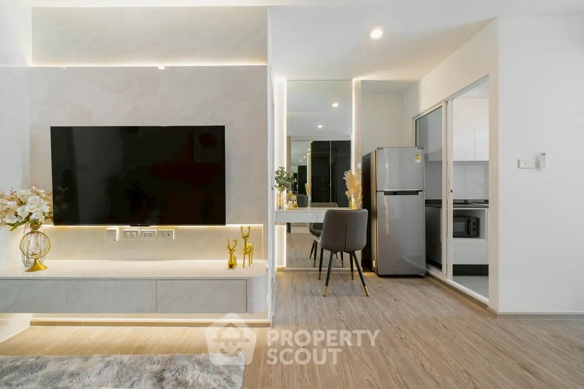 Modern living room with sleek TV setup and stylish dining area, featuring contemporary decor and elegant lighting.
