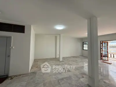 Spacious open-plan living area with tiled flooring and balcony access