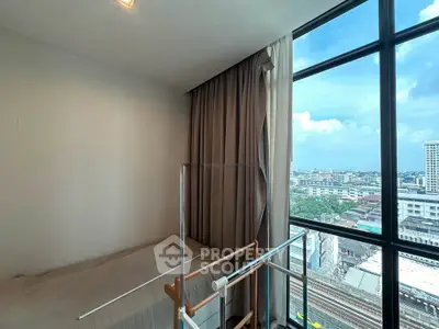 Cozy bedroom with large window offering stunning city view, perfect for urban living.