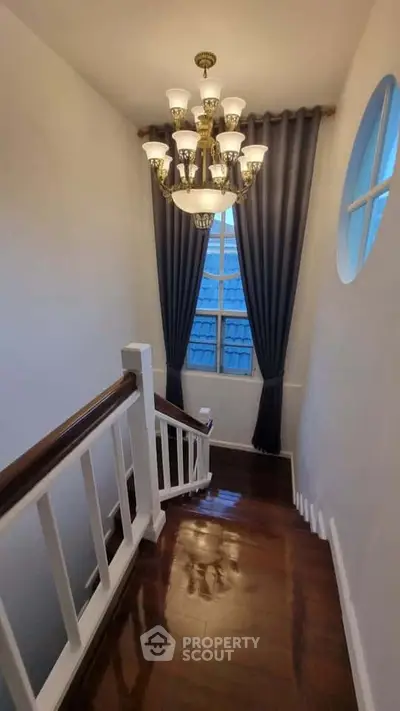 Elegant staircase with chandelier and window drapes in a modern home