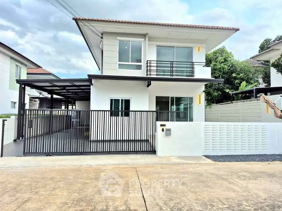 Modern two-story house with sleek design and gated driveway in a suburban neighborhood.