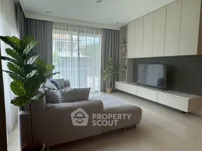 Modern living room with sleek furniture and large windows offering natural light.