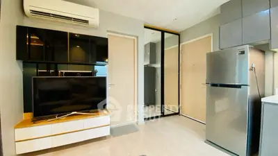 Modern living room with sleek design, featuring a TV, air conditioning, and a stainless steel fridge.