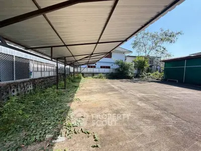 Spacious outdoor parking area with covered carport and surrounding greenery.
