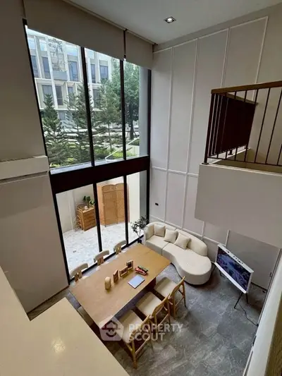 Stunning duplex living room with high ceilings and large windows overlooking a serene garden.