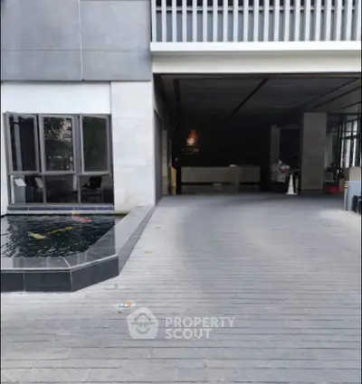 Modern building entrance with sleek design and water feature, ideal for luxury living.