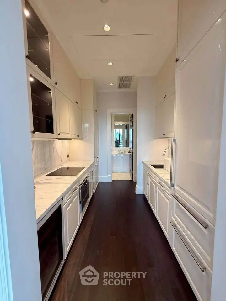 Luxurious modern kitchen with sleek white cabinetry and dark wood flooring