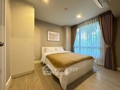Cozy bedroom with modern decor and large window offering natural light.