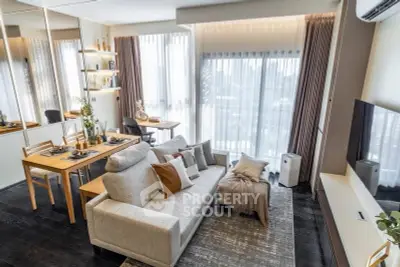Modern living room with stylish decor and dining area, featuring large windows and cozy seating.