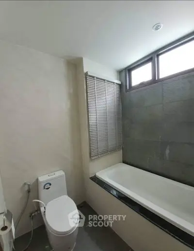 Modern bathroom with bathtub and natural light from large window.