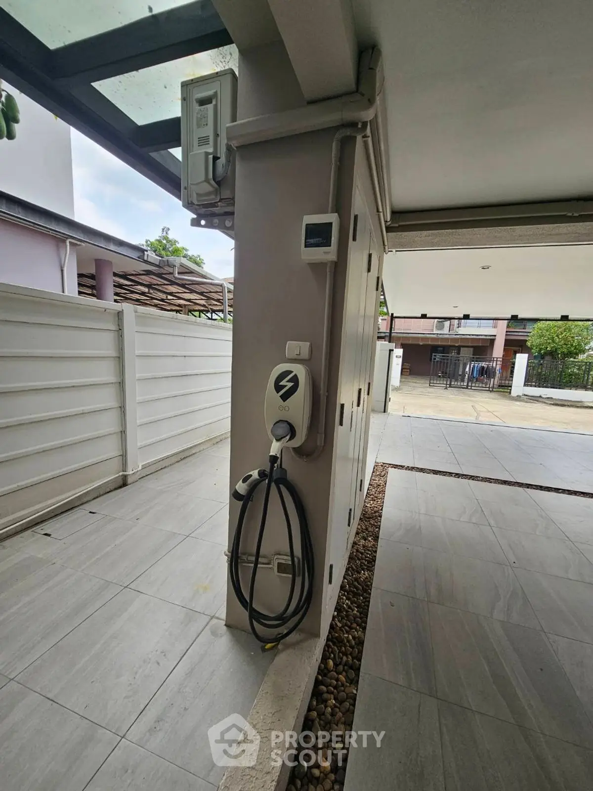 Modern home exterior with electric vehicle charging station in covered parking area