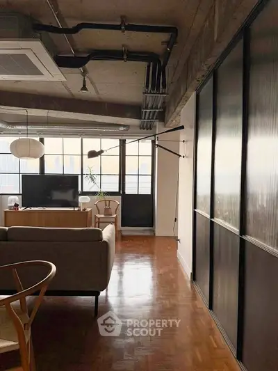 Stylish industrial-style living room with large windows and modern furniture