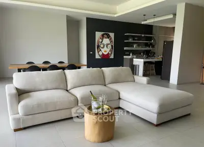 Spacious modern living room with elegant sofa and open kitchen layout, perfect for entertaining.