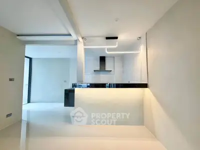 Modern kitchen with sleek design and open layout, featuring stylish lighting and glossy tiles.