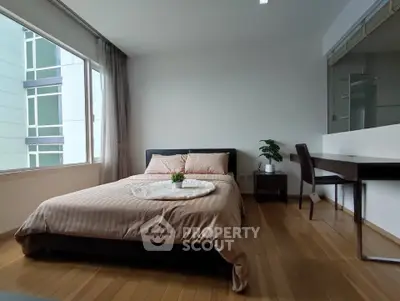 Spacious bedroom with modern decor and large window offering natural light.