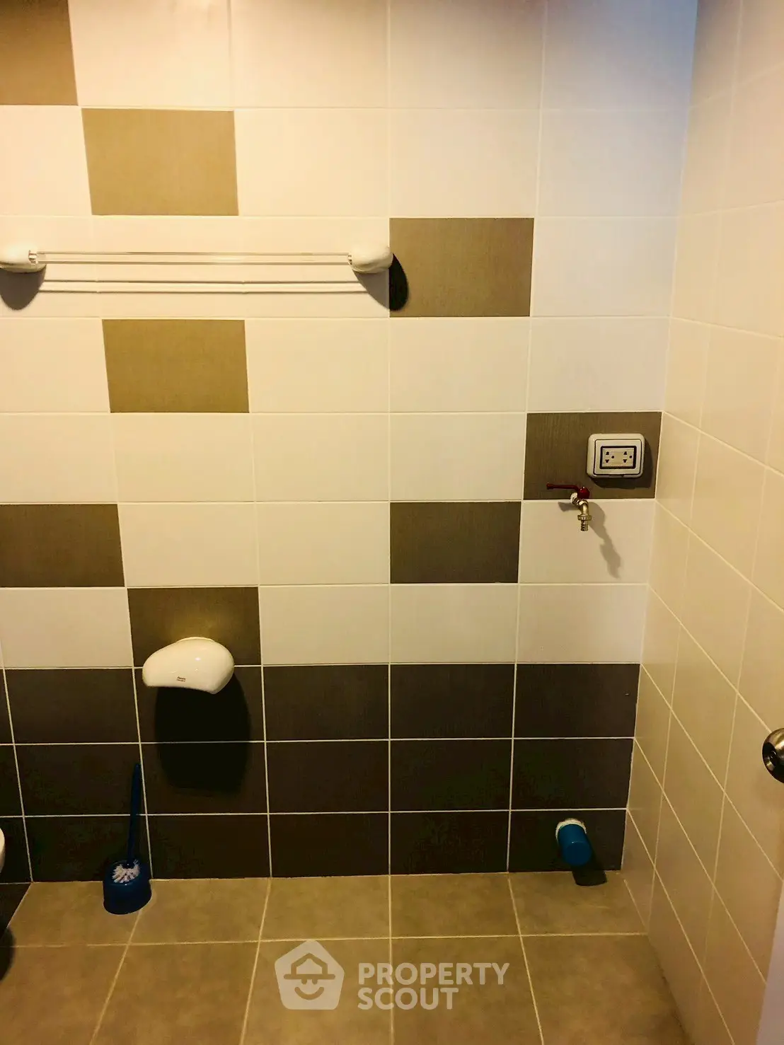 Modern bathroom with tiled walls and floor, featuring a towel rack and plumbing fixtures.