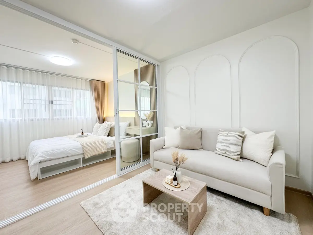 Modern open-plan living room with cozy bedroom, elegant decor, and natural light.