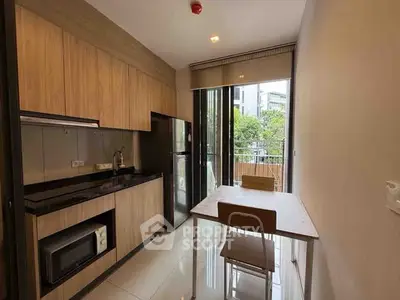 Modern kitchen with sleek cabinetry and balcony view in urban apartment.