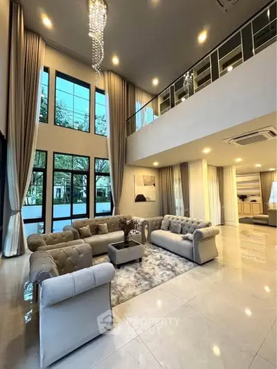 Luxurious double-height living room with elegant chandeliers and plush seating in modern home.