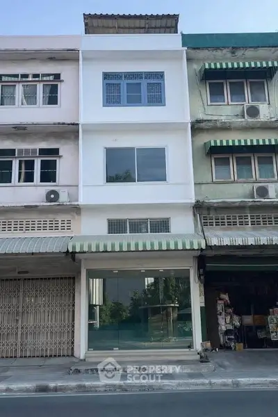 Charming three-story commercial building with large glass storefront and residential upper floors.