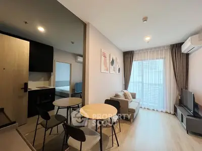 Modern living room with cozy sofa, dining area, and natural light from large window.