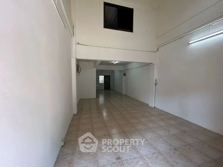 Spacious open-plan interior with tiled flooring and high ceiling, ideal for versatile use.