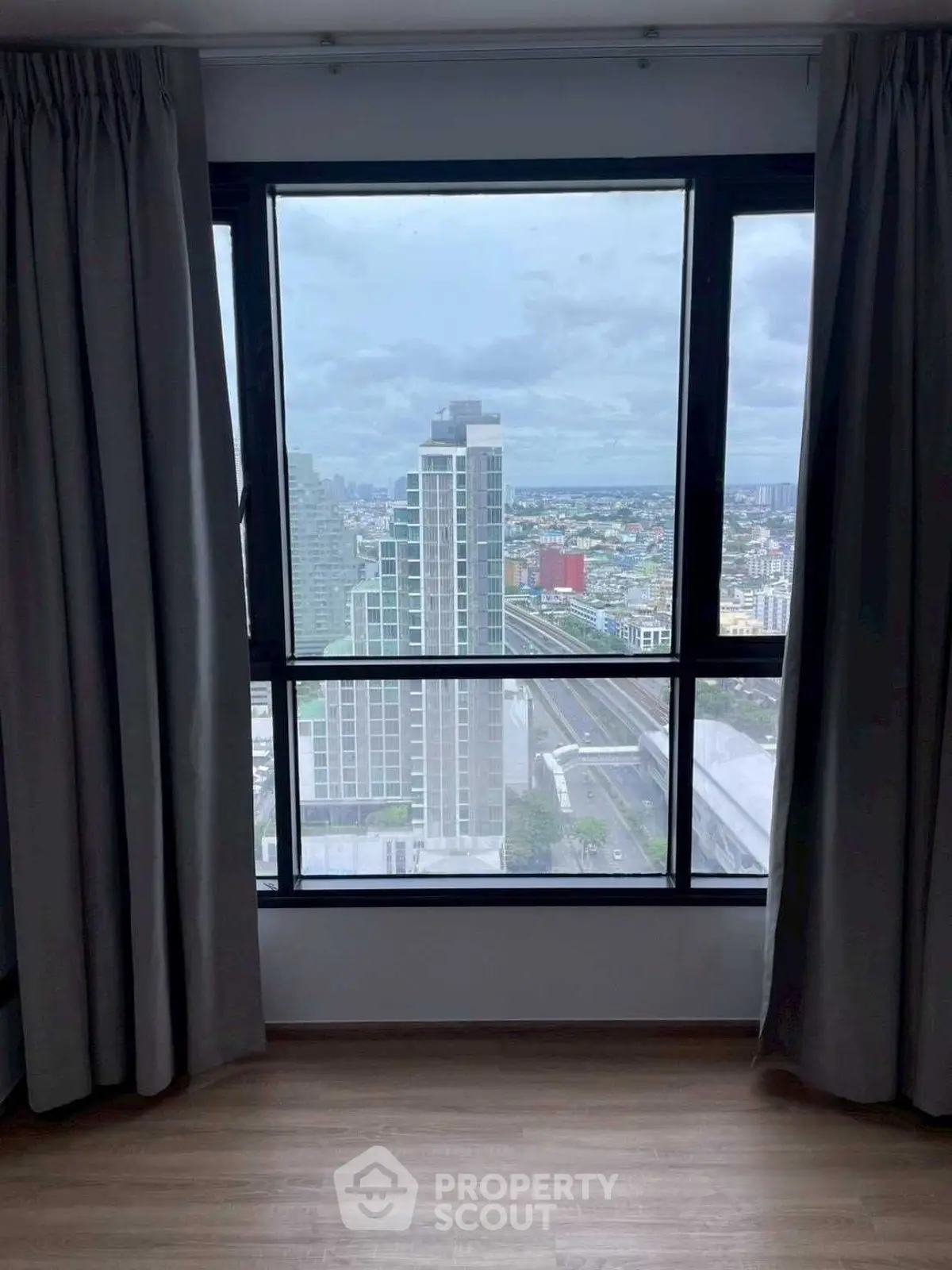Stunning cityscape view from high-rise apartment window with modern curtains.