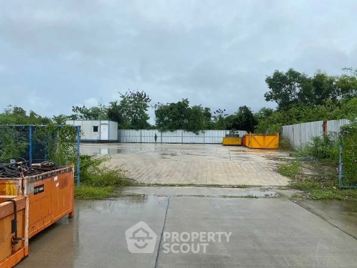 Spacious industrial outdoor area with storage containers and greenery, ideal for commercial use.