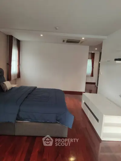 Spacious bedroom with elegant wooden flooring and modern furnishings
