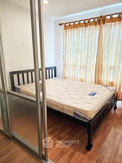 Cozy bedroom with wooden flooring and large window for natural light