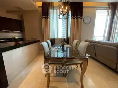 Elegant dining area with luxurious marble table and modern kitchen in open layout apartment.