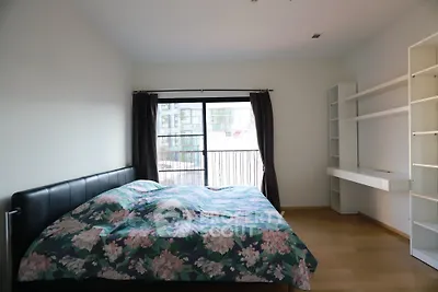 Spacious bedroom with modern decor and large window offering natural light.