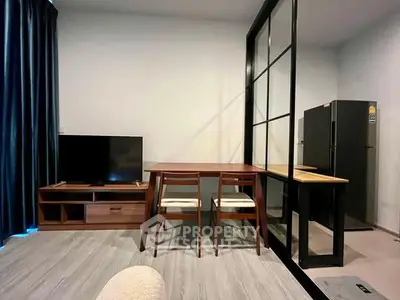 Modern living room with sleek furniture and glass partition, featuring a TV and dining area.