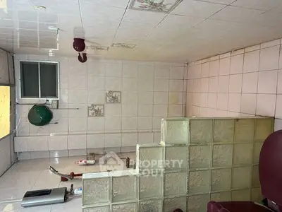 Spacious tiled kitchen with unique glass block partition and modern appliances.