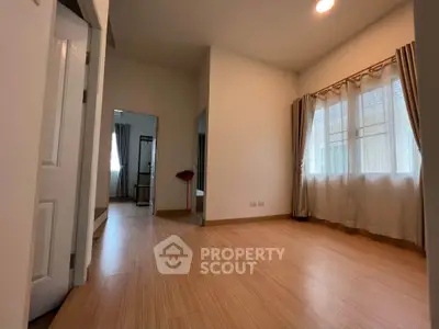 Spacious empty room with wooden flooring and large windows, perfect for customization.