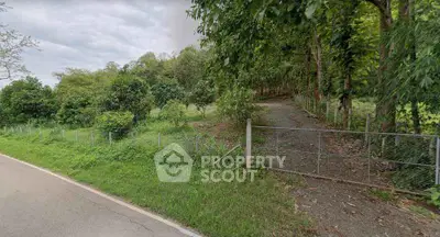Scenic view of lush green land with trees and pathway, ideal for real estate development.